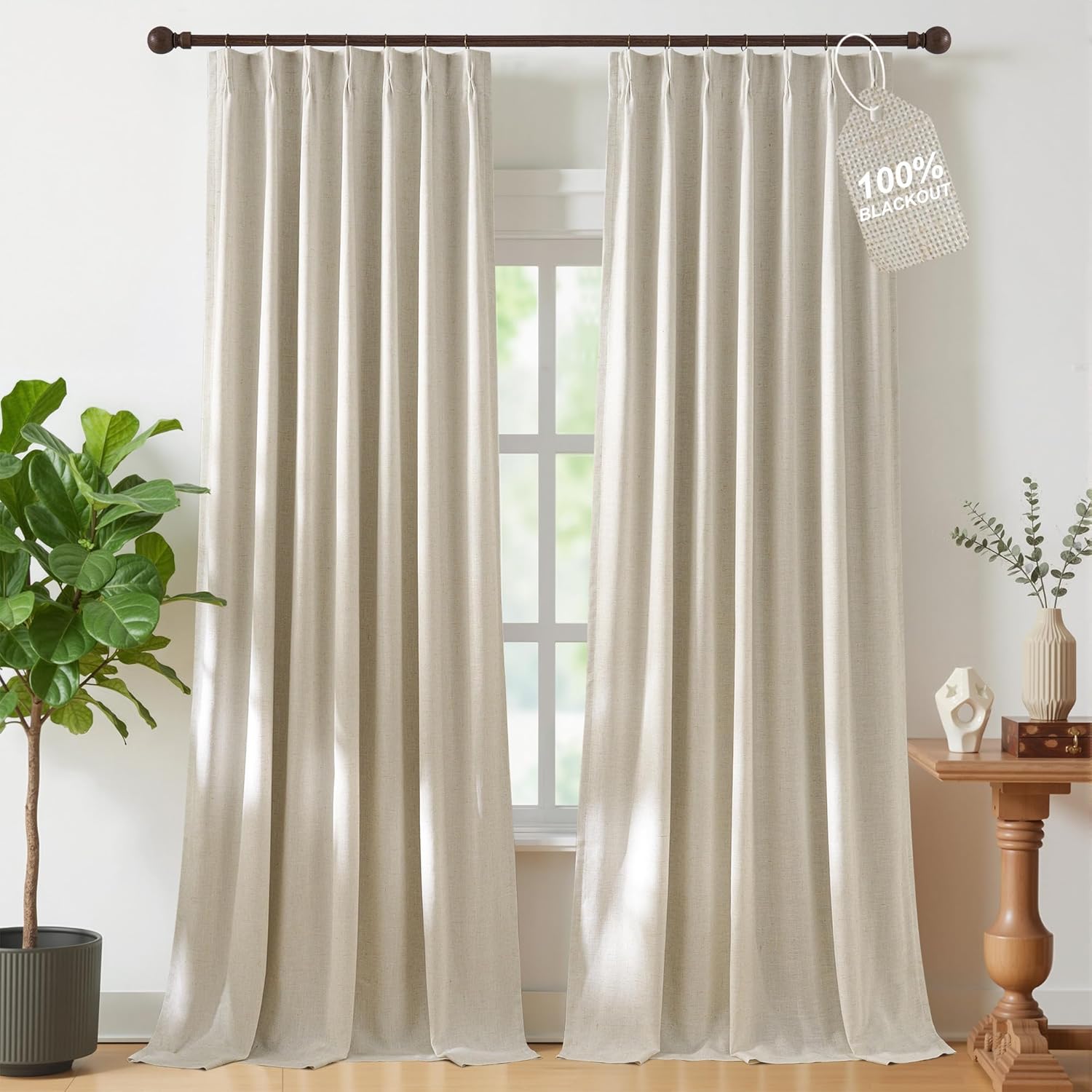 Light beige linen-look pleated blackout curtains hang from a dark rod, covering a window.