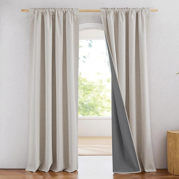 Light beige linen-textured rod pocket curtains with dark gray blackout lining, hanging on a wooden rod.