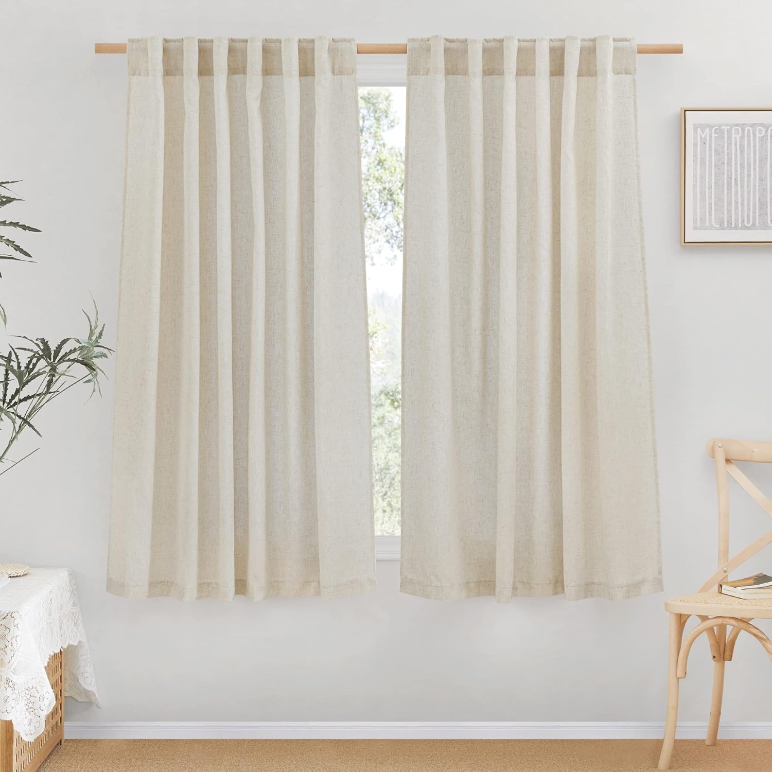 Light beige linen tab top curtains hanging on a wooden rod, creating a natural, rustic aesthetic.