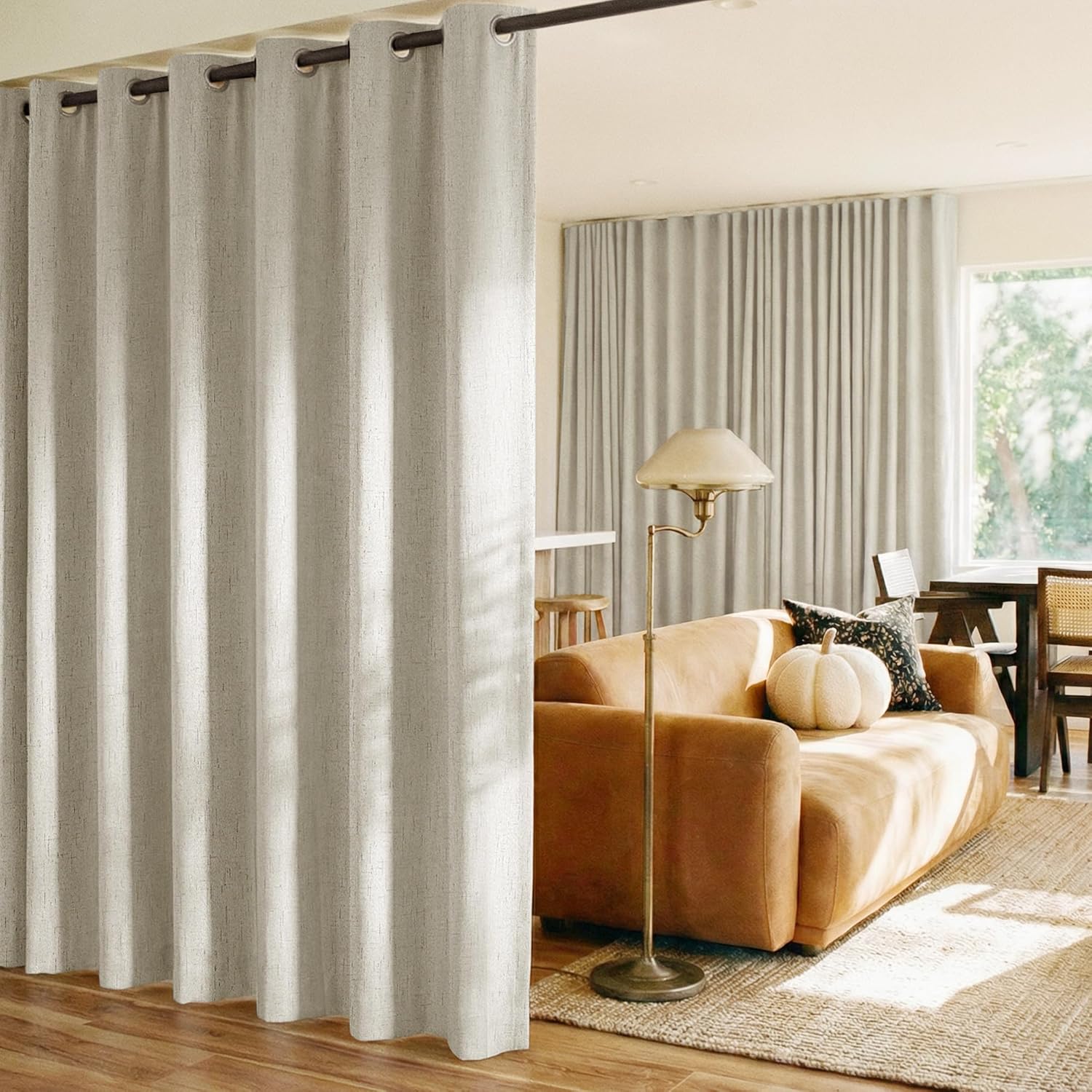 Light beige textured grommet top curtain dividing a modern living room from a dining space.