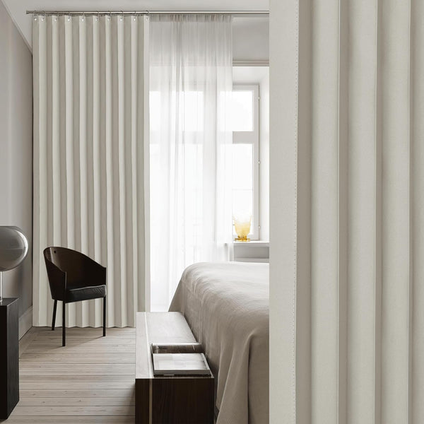 Light beige wave fold curtains and matching textured room divider panel in a modern bedroom setting.