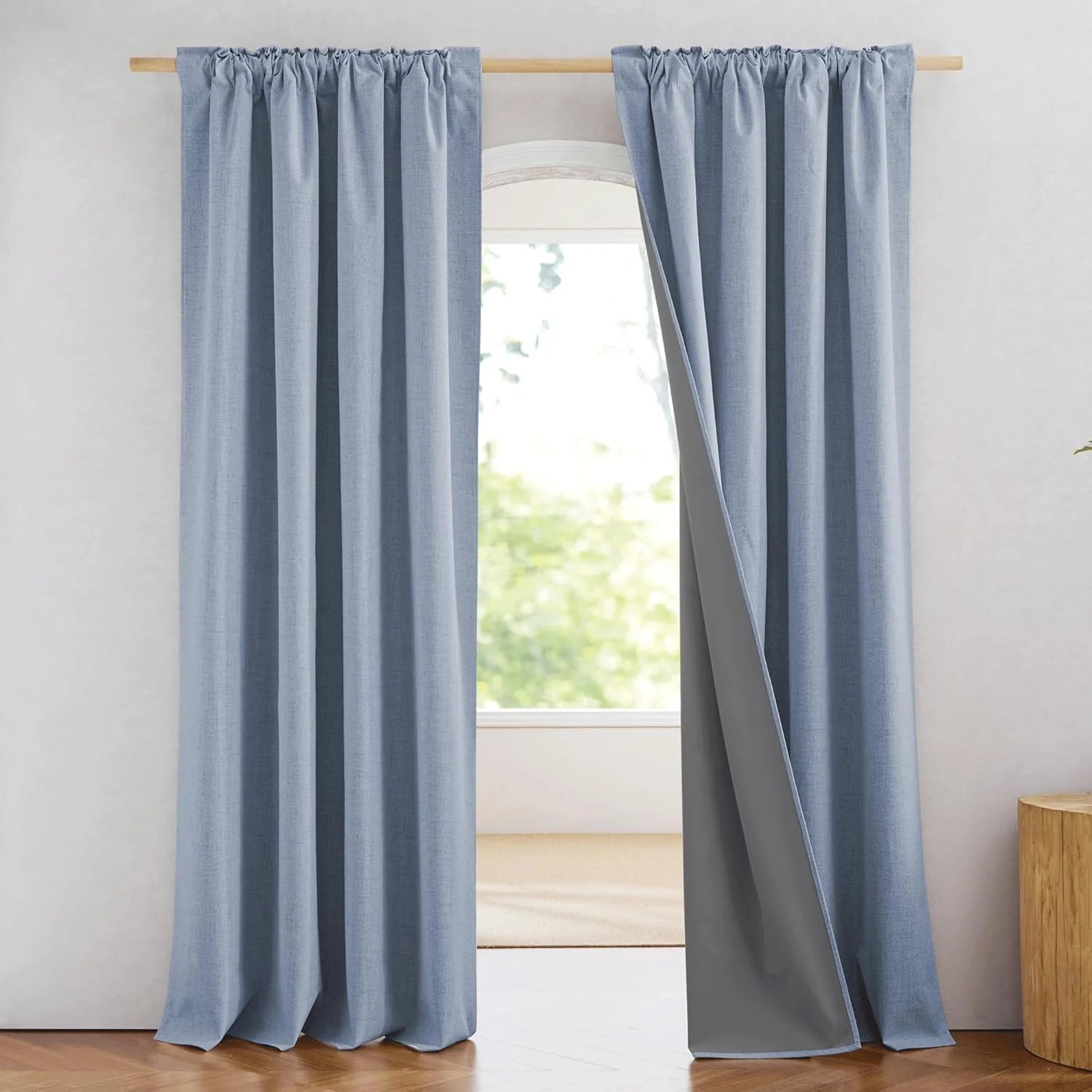 Light blue linen-look blackout curtains with rod pocket top on a wooden curtain rod