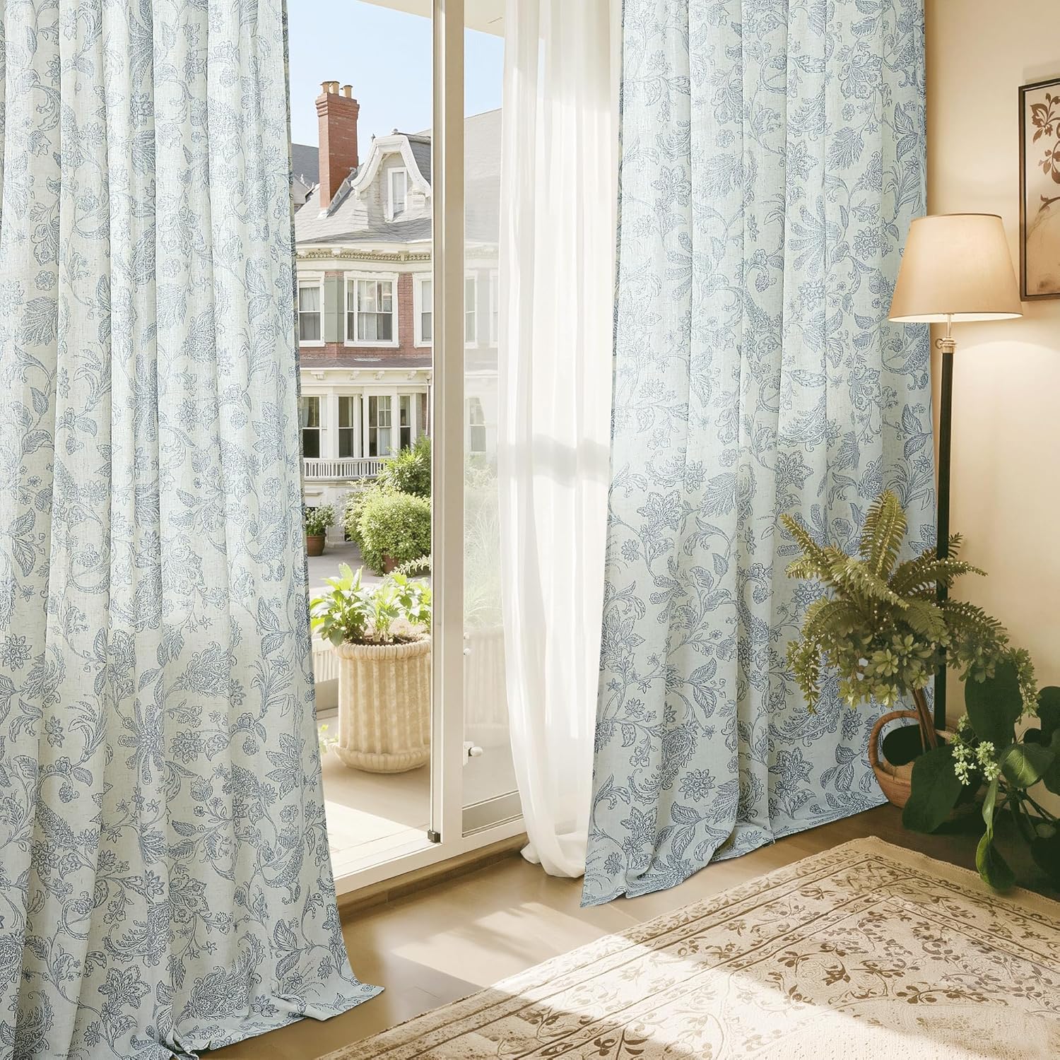 Floor-length light blue curtains with delicate floral pattern covering a large glass door.