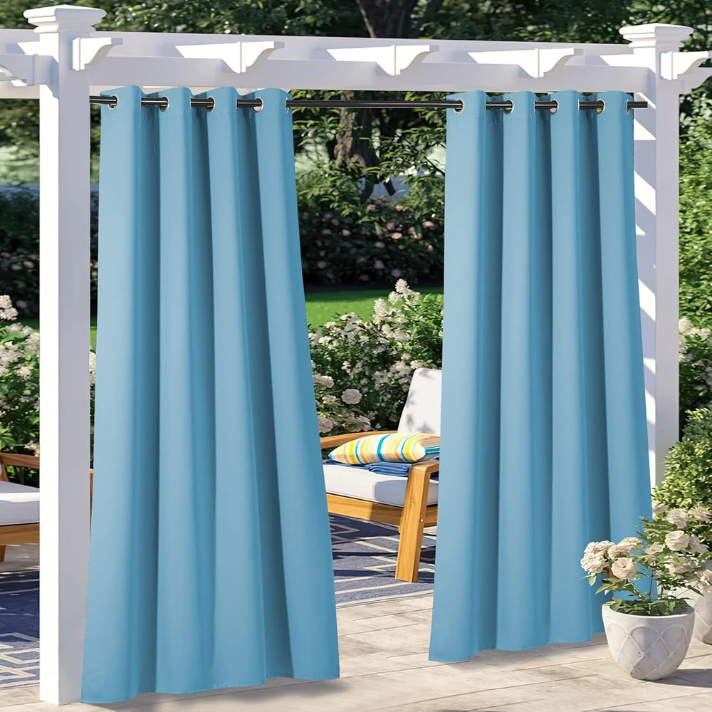 Light blue grommet top outdoor curtains hanging on a white pergola in a lush patio setting with furniture.