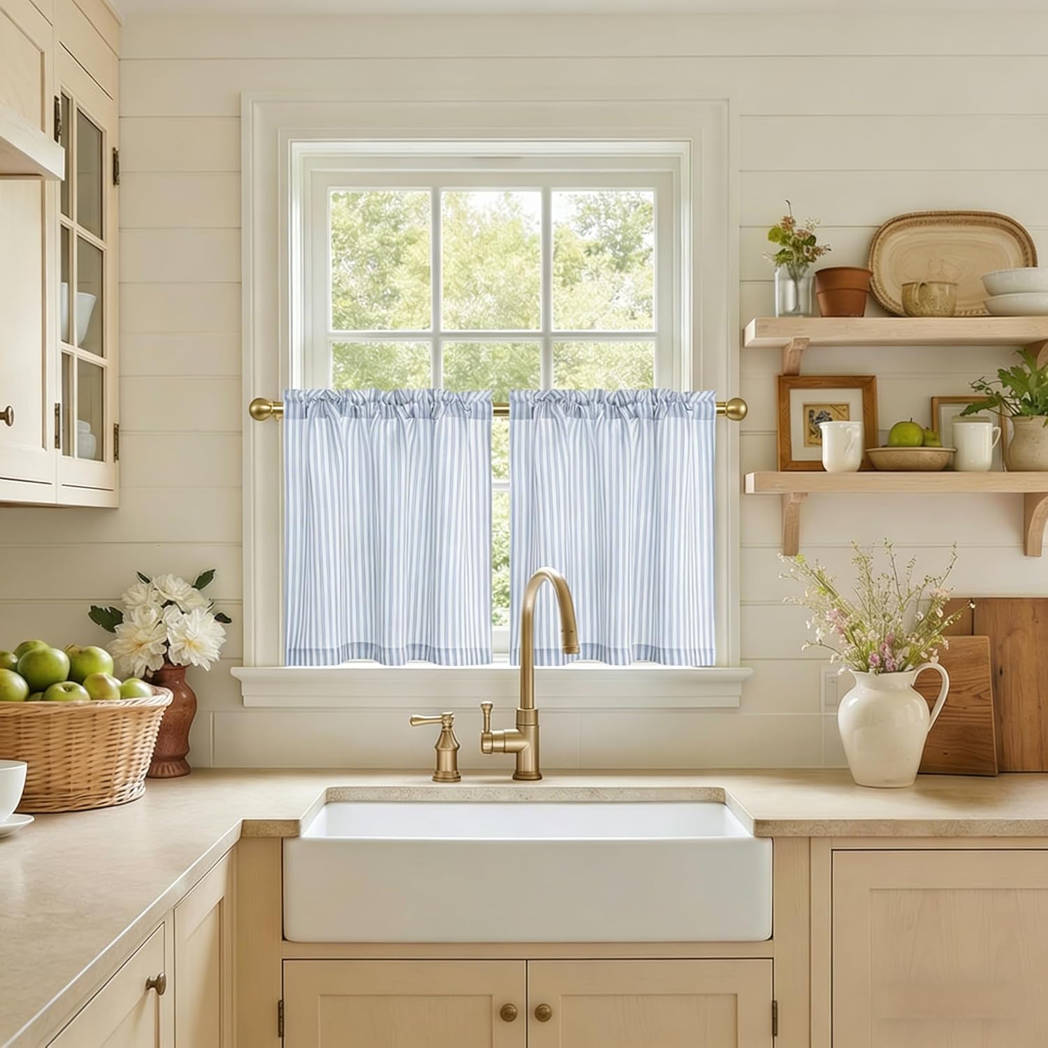Light blue and white striped cafe curtains hanging in a bright farmhouse kitchen window.