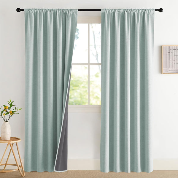 Light blue textured blackout curtain panels on a black rod, one revealing its dark gray lining.