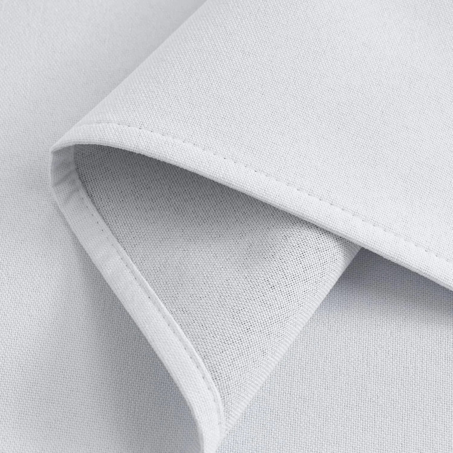 Close-up of light-colored, finely woven fabric with a folded hem and visible stitching.