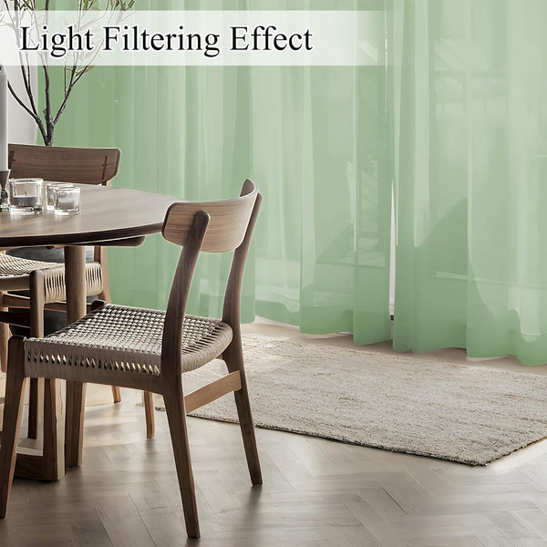 Sage green sheer curtains softly filtering sunlight in a modern dining room.