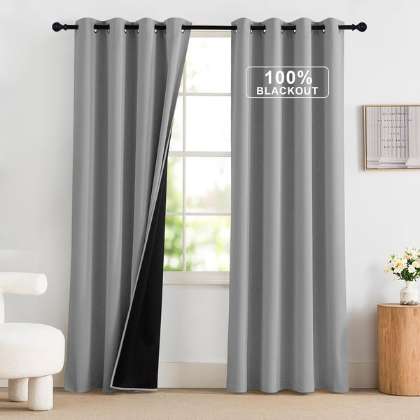 Light gray 100% blackout curtains with a visible black lining and grommet top, hanging on a dark rod.