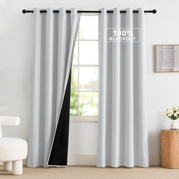 Light gray 100% blackout curtains with black lining and grommet top, hanging on a rod.