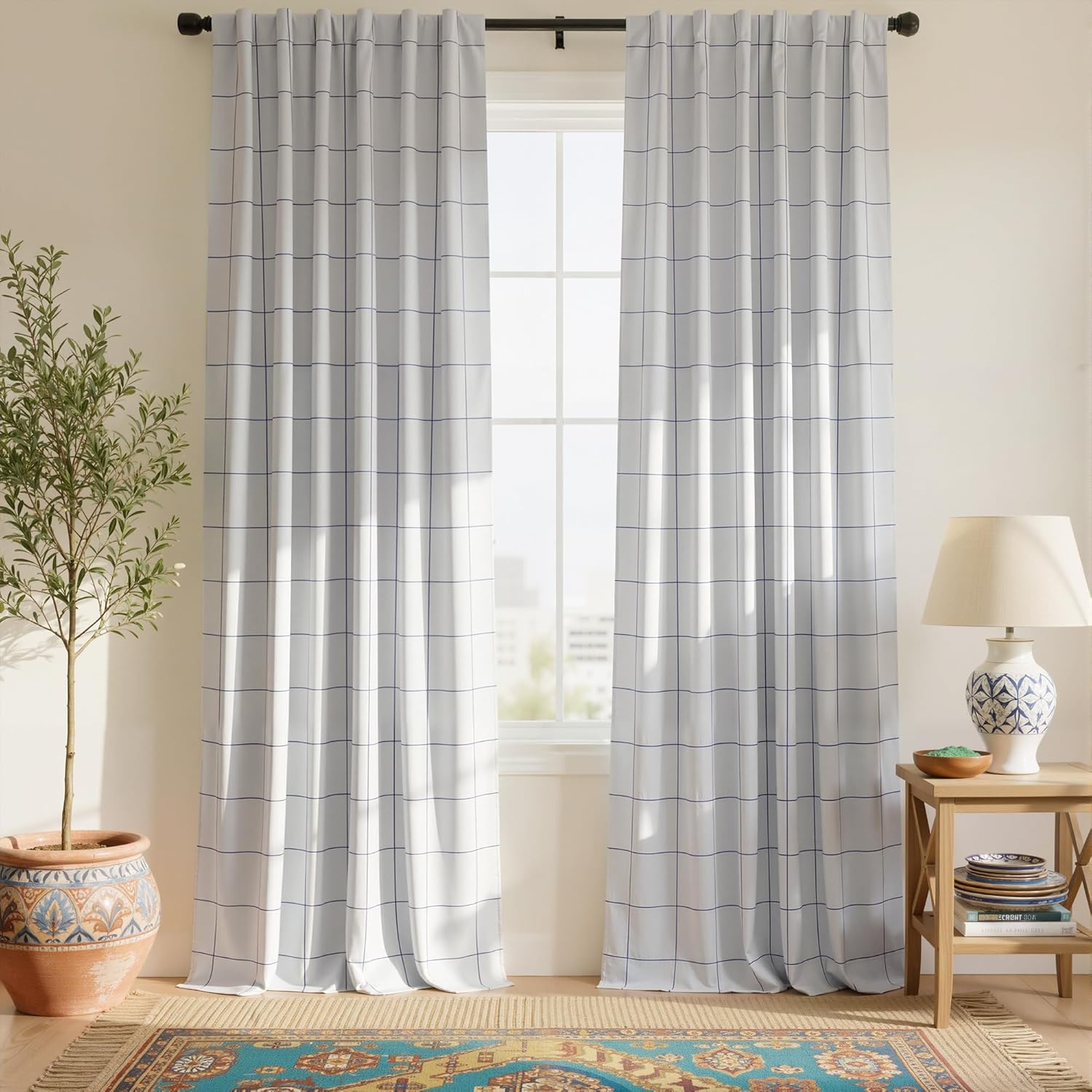 Light gray curtains with a thin blue grid pattern hanging on a dark rod, filtering sunlight.