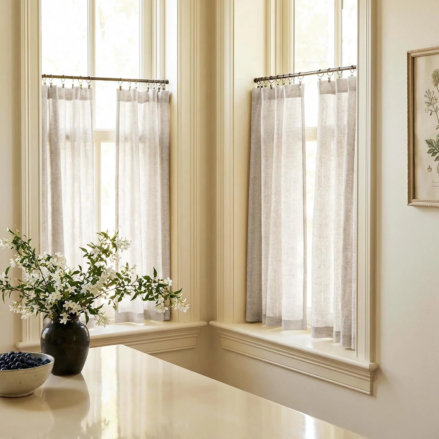 Light gray linen cafe curtains on bronze rods in a sunny kitchen nook