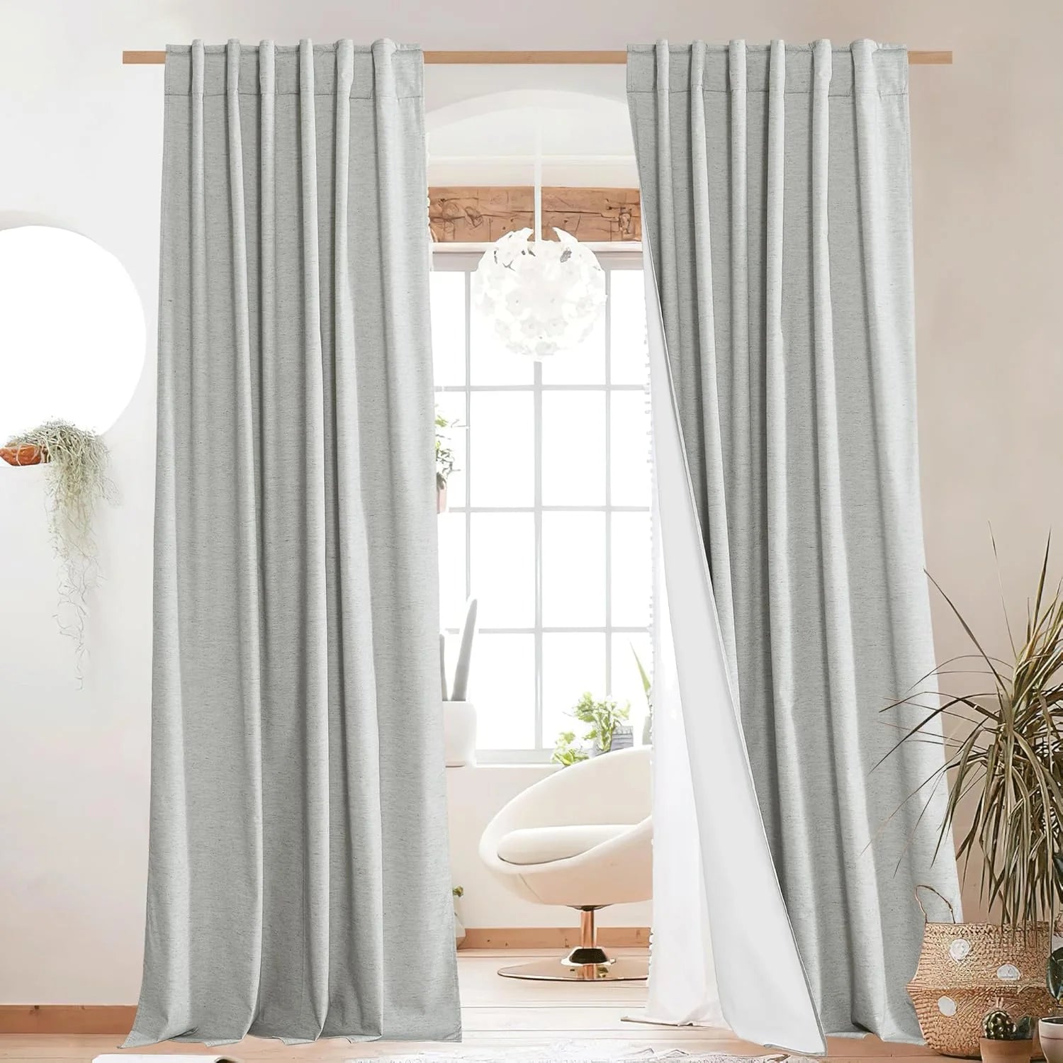 Light gray linen-look curtain panels hanging on a wooden rod in a bright modern room