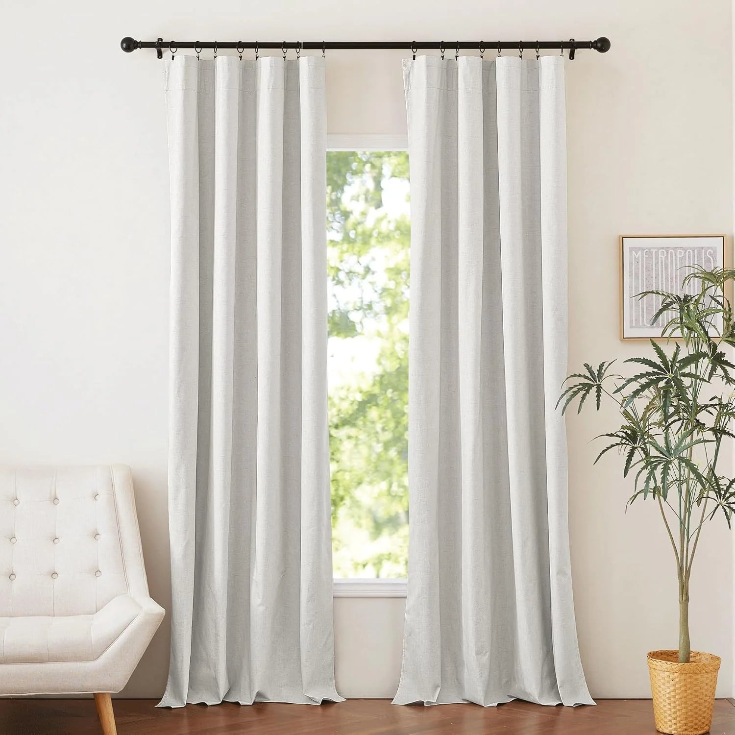Light gray linen-look curtains hanging on a black rod in a bright neutral room