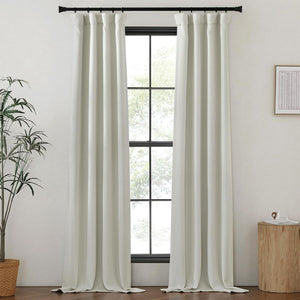 Light gray textured back tab curtains on a black rod, softly pooling on the dark wood floor.