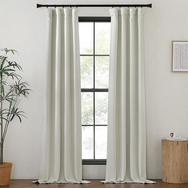 Light gray textured back tab curtains on a black rod, softly pooling on the dark wood floor.