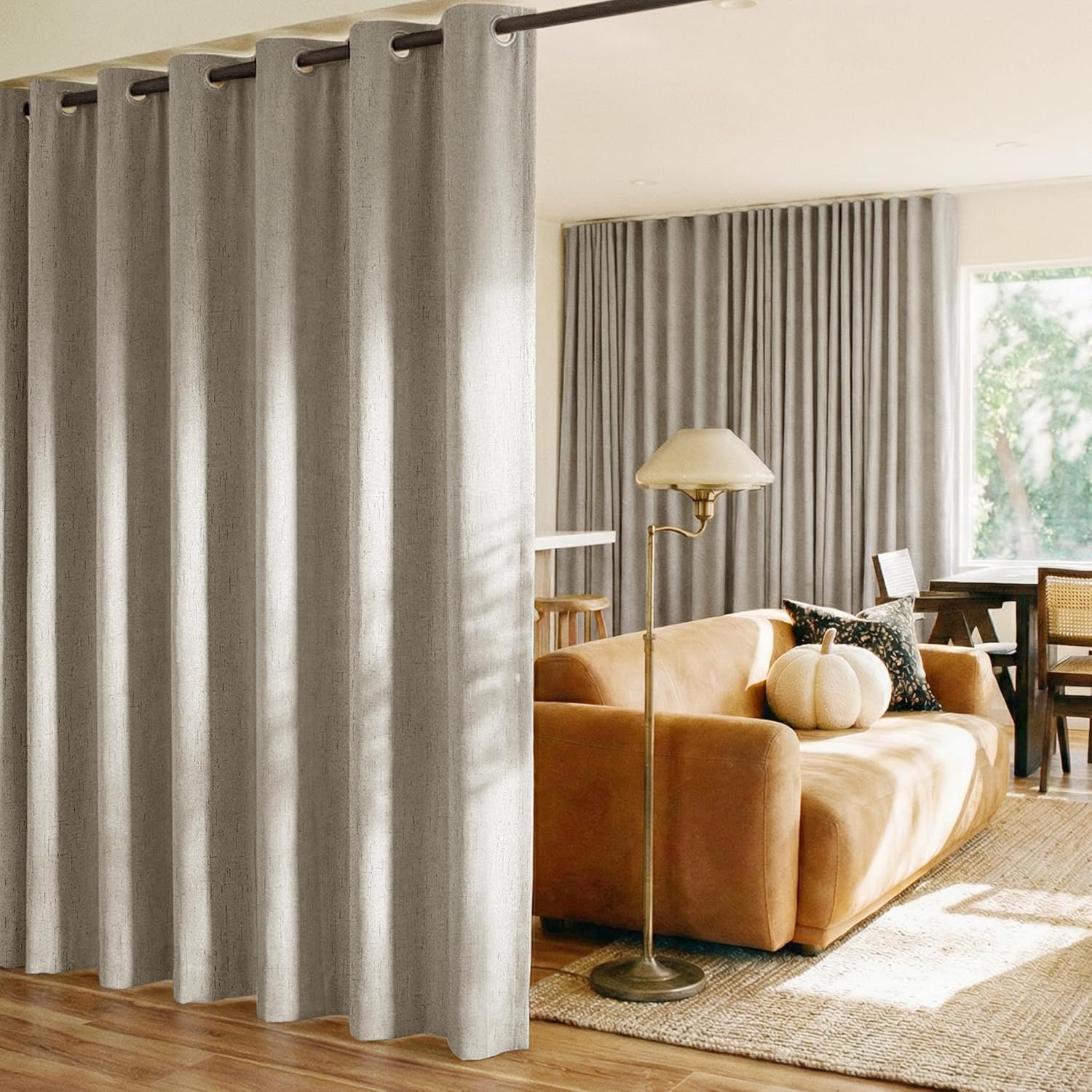 Light gray textured grommet top room divider curtain on a dark rod, partitioning a modern living room.