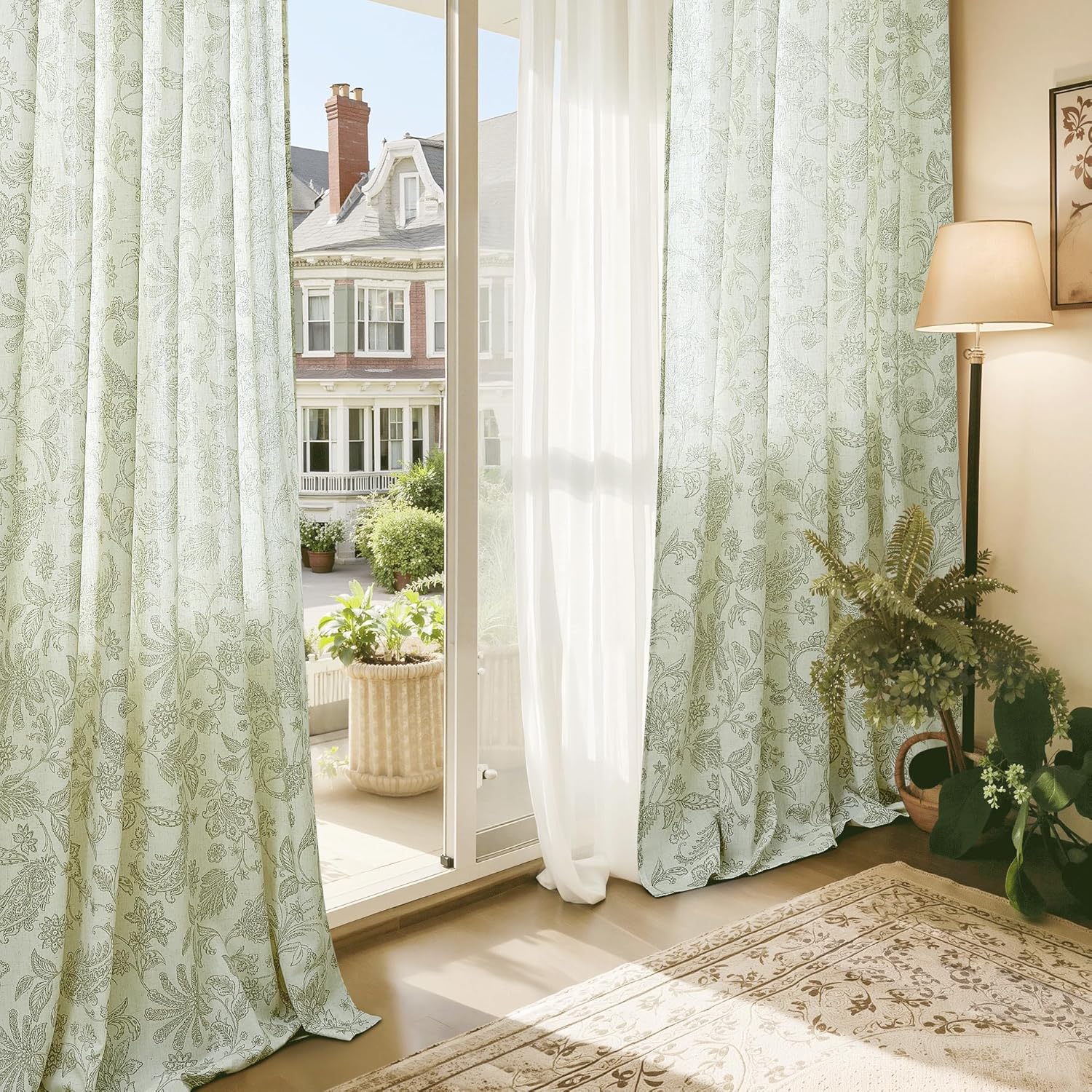 Light green patterned curtains with delicate floral paisley design hanging by a glass door in a bright, classic room.