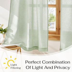 Light green and white gingham patterned curtains hanging by a wooden window, filtering natural light.