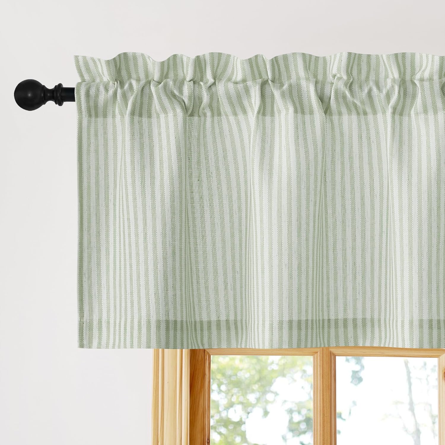 Light green and white striped rod pocket window valance hanging on a black rod above a wooden window frame.