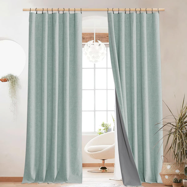 Light green textured blackout curtains with a grey lining and ring top hanging in a modern living room.