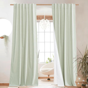 Light green textured linen-blend blackout curtains with white lining, hanging on a wooden rod.