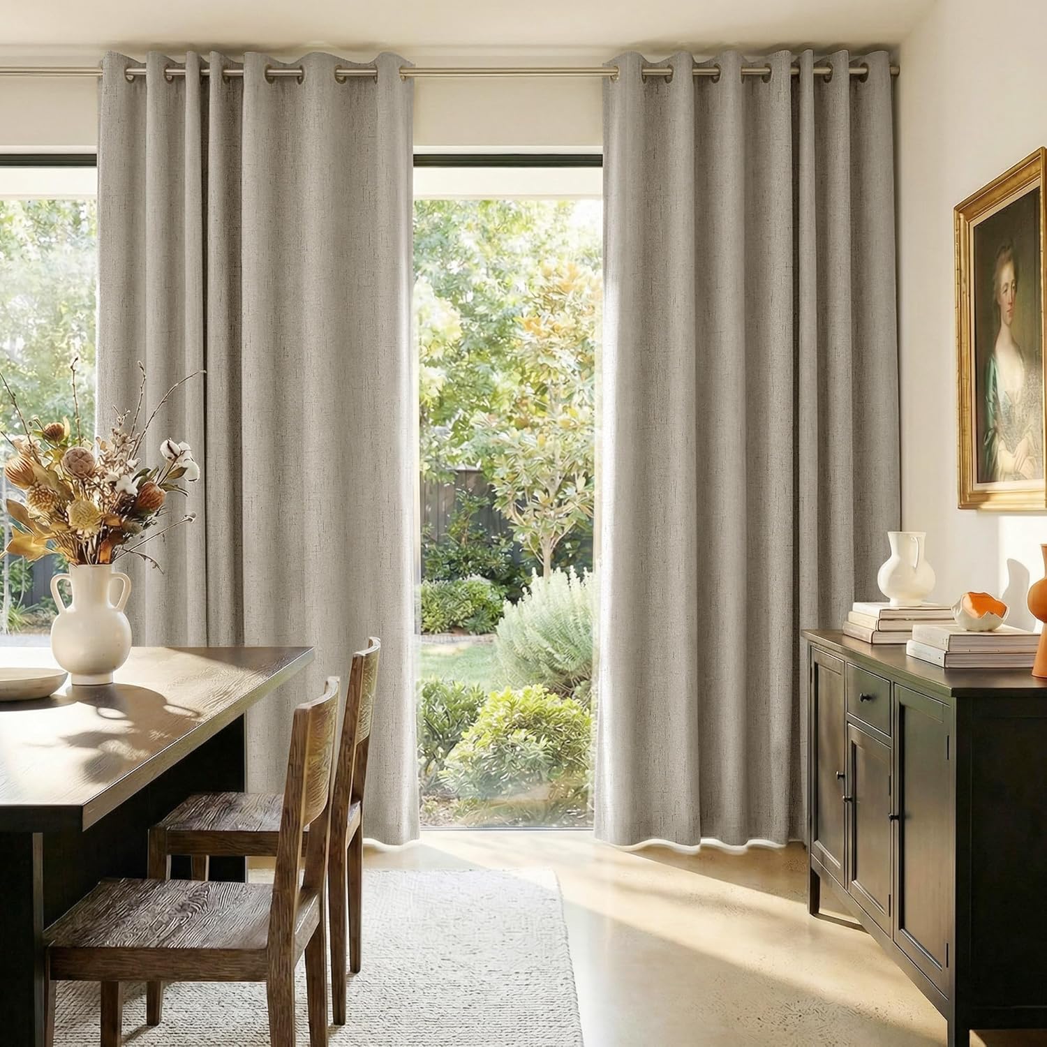 Light greige textured grommet top curtains covering large windows in a modern dining room.