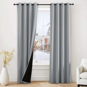 Light grey grommet top blackout curtains, one panel showing black lining, on a black rod.
