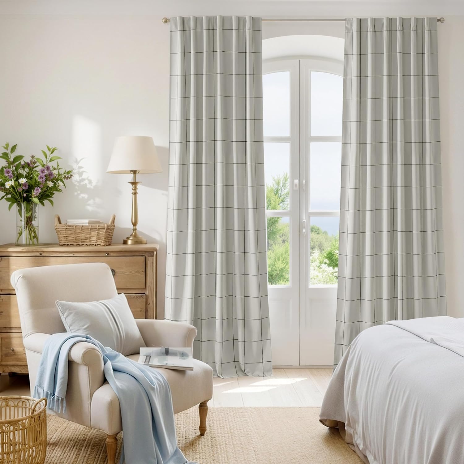 Light grey curtains with a black grid windowpane check pattern and pleated tops, hung in a bright bedroom.