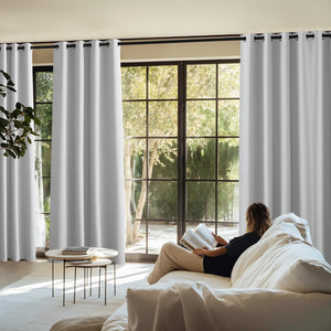 Light grey blackout grommet-top curtains on a black rod, installed in a bright modern living room.