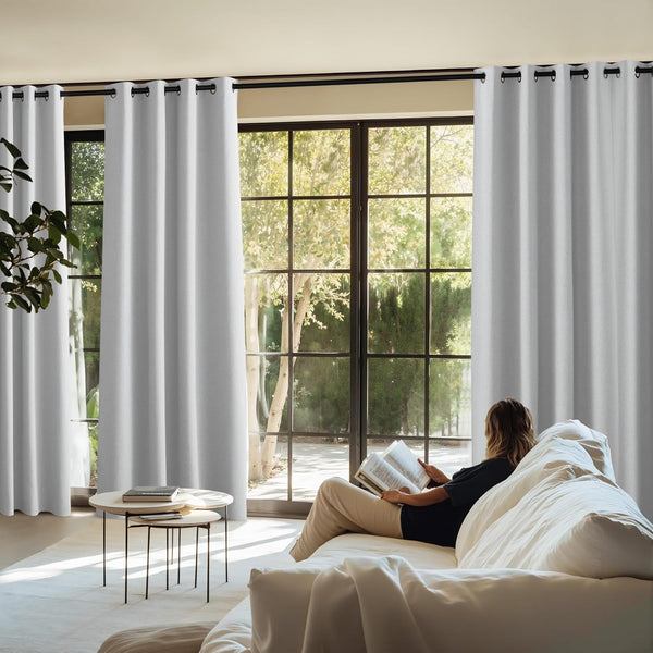 Light grey blackout grommet-top curtains on a black rod, installed in a bright modern living room.