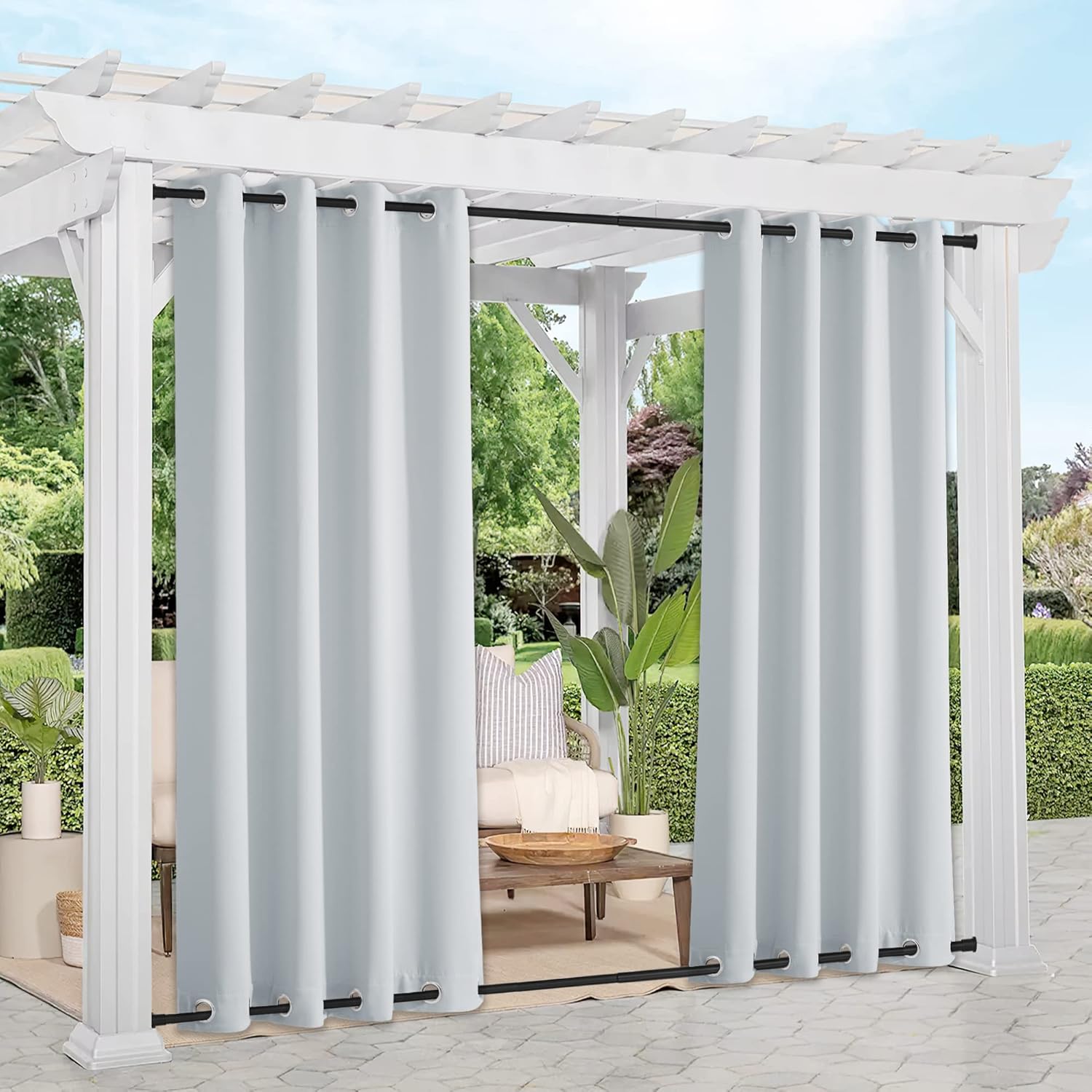 Light grey outdoor blackout curtains with black grommets and weighted hem, on a patio pergola.