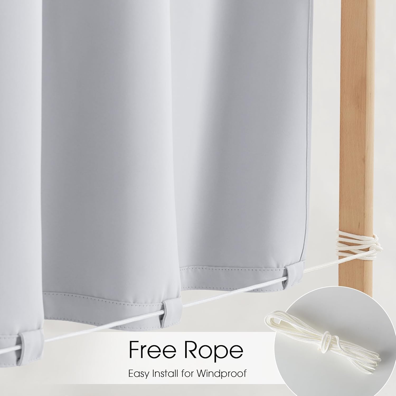 Light grey outdoor curtains with bottom loops secured by white rope to a wooden post, illustrating windproof installation.