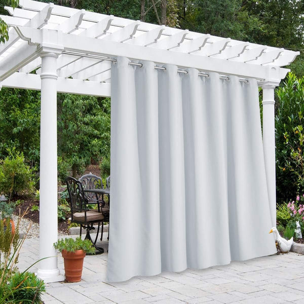 Light grey outdoor patio curtains with silver grommets hanging from a white pergola, offering privacy for a seating area.