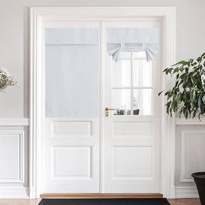 Light grey fabric panel and tie-up shades on a white French door, providing privacy and light control.
