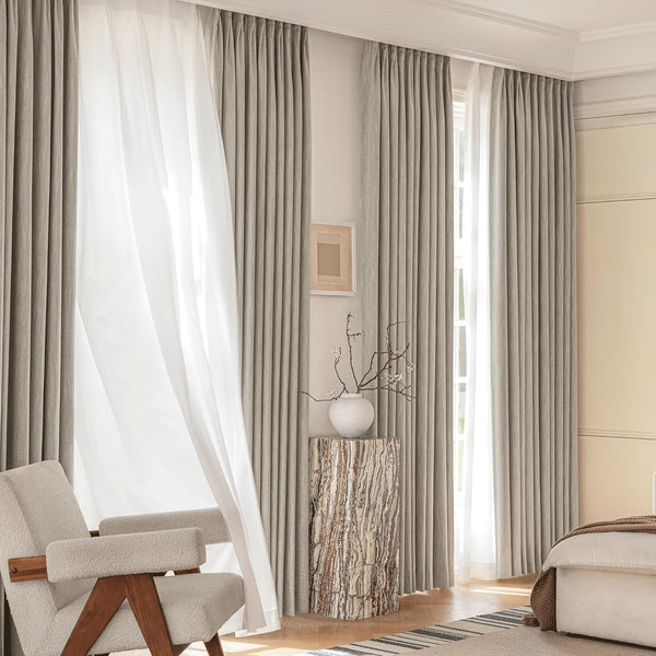 Light grey pleated drapes and white sheer curtains provide elegant light control in a modern room.