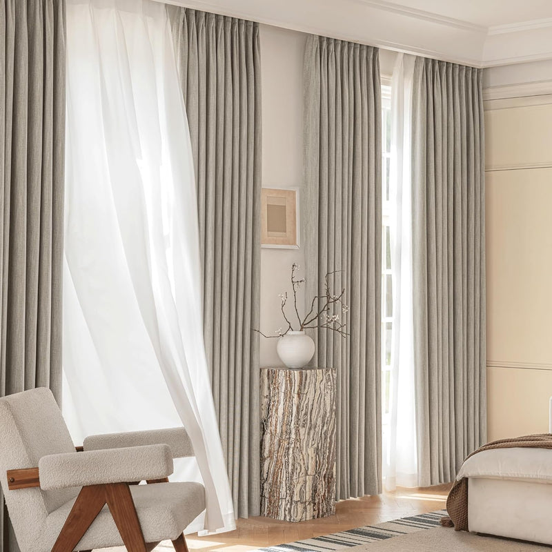 Light grey pleated drapes and white sheer curtains provide elegant light control in a modern room.