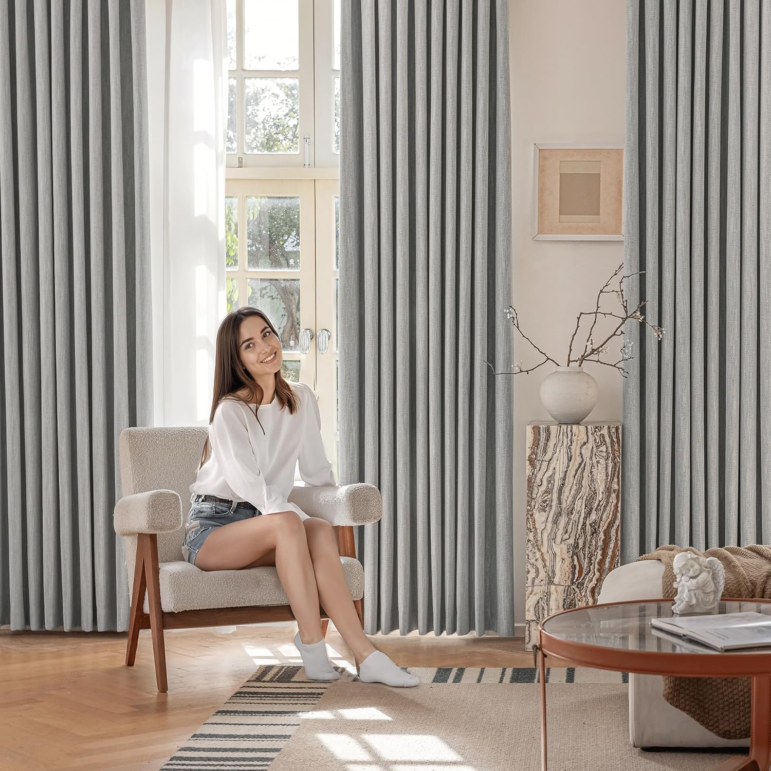 Elegant light grey pleated curtains with a subtle texture in a bright modern living room setting.