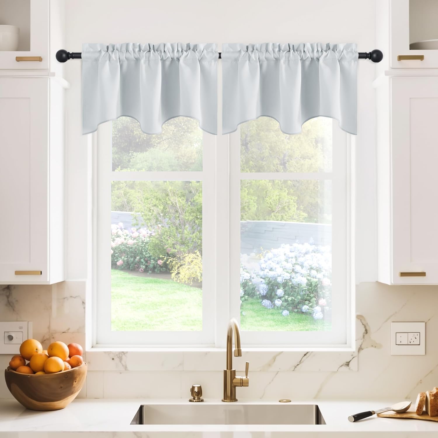 Light grey scalloped valance curtain with rod pocket, hanging on a black rod above kitchen sink.