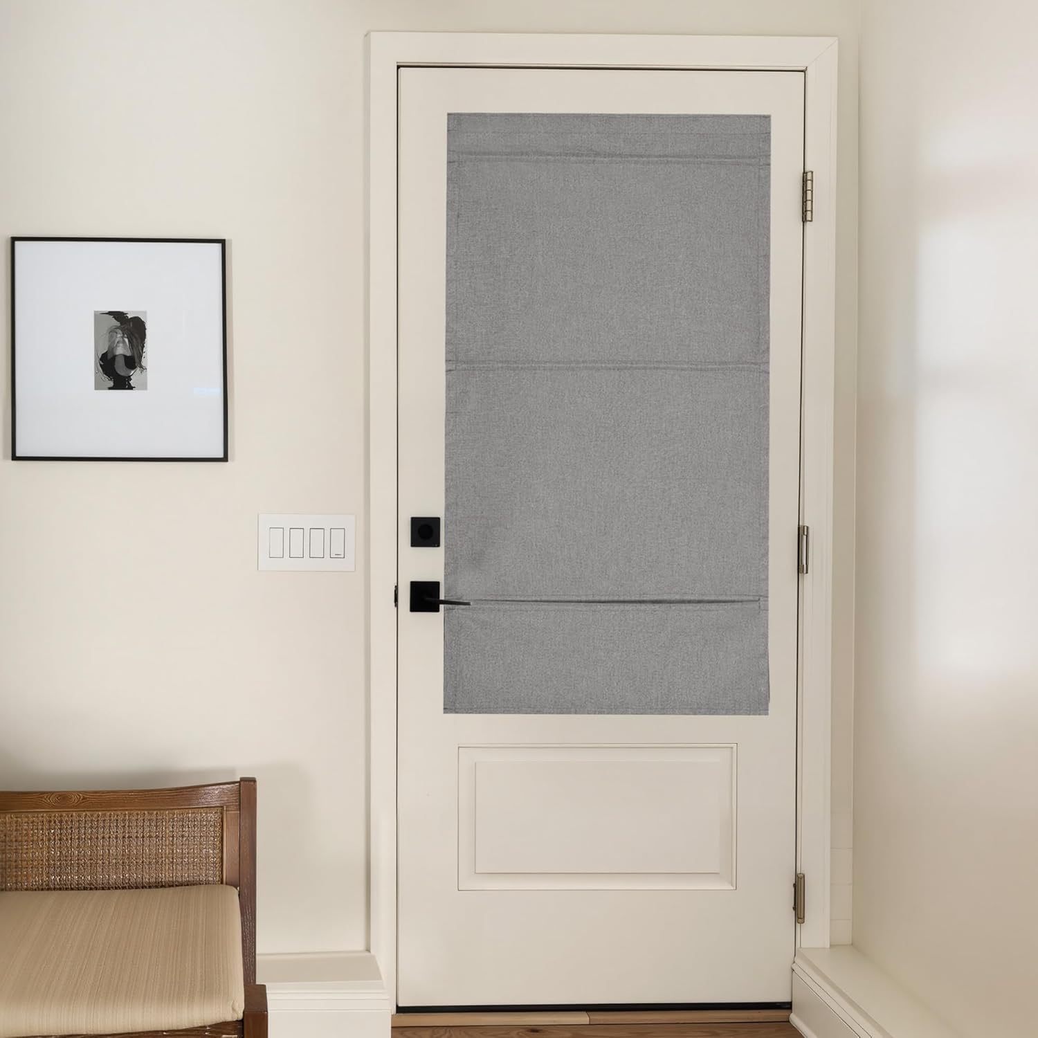 Light grey textured fabric roman shade with flat folds mounted on a white interior door.