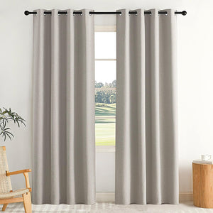 Light grey textured blackout curtains with metal grommet top on a black rod, in a bright room.