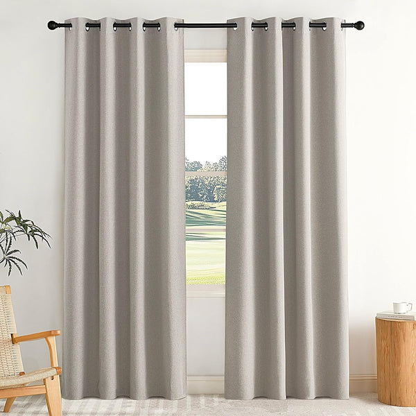 Light grey textured blackout curtains with metal grommet top on a black rod, in a bright room.