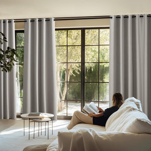 Light grey textured grommet curtains drawn across large windows in a modern living room