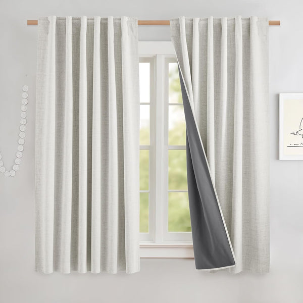 Pair of light grey textured curtains with visible dark grey blackout lining on a wood rod.