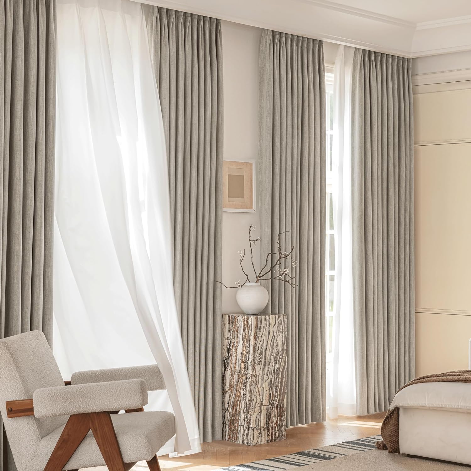 Light grey textured pinch pleat curtains paired with white sheer panels. Hung floor-to-ceiling in a modern room with natural light.