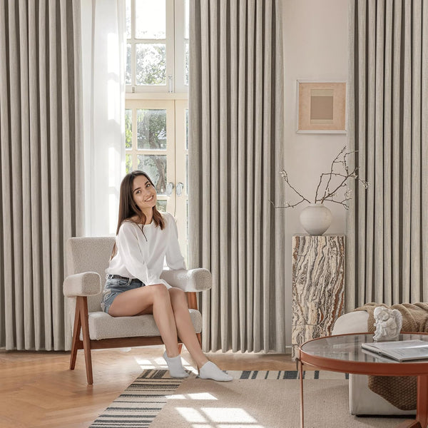 Light grey textured pleated linen curtains with full uniform folds in a bright living room.