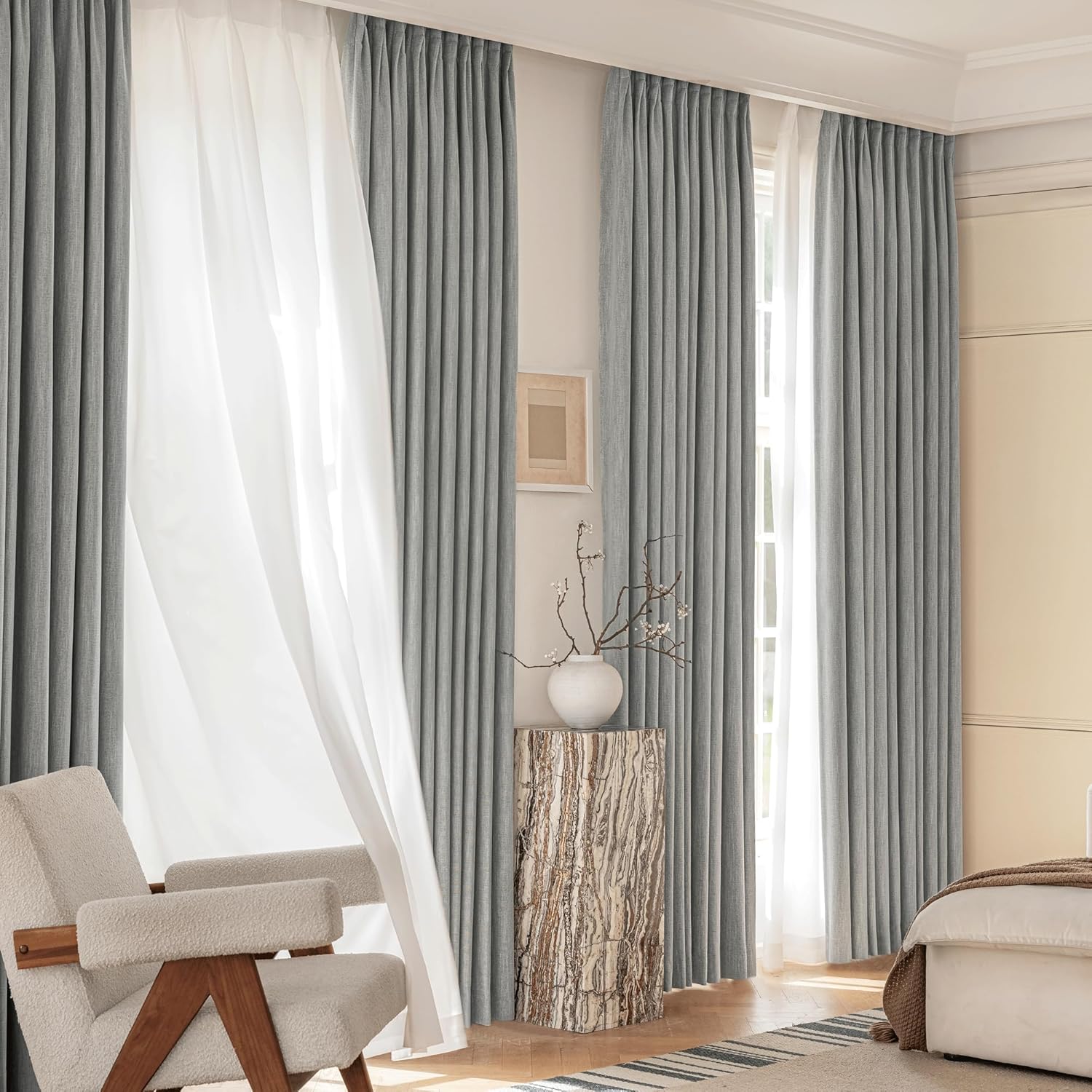 Light grey textured pleated curtains paired with white sheer drapes on a large window.