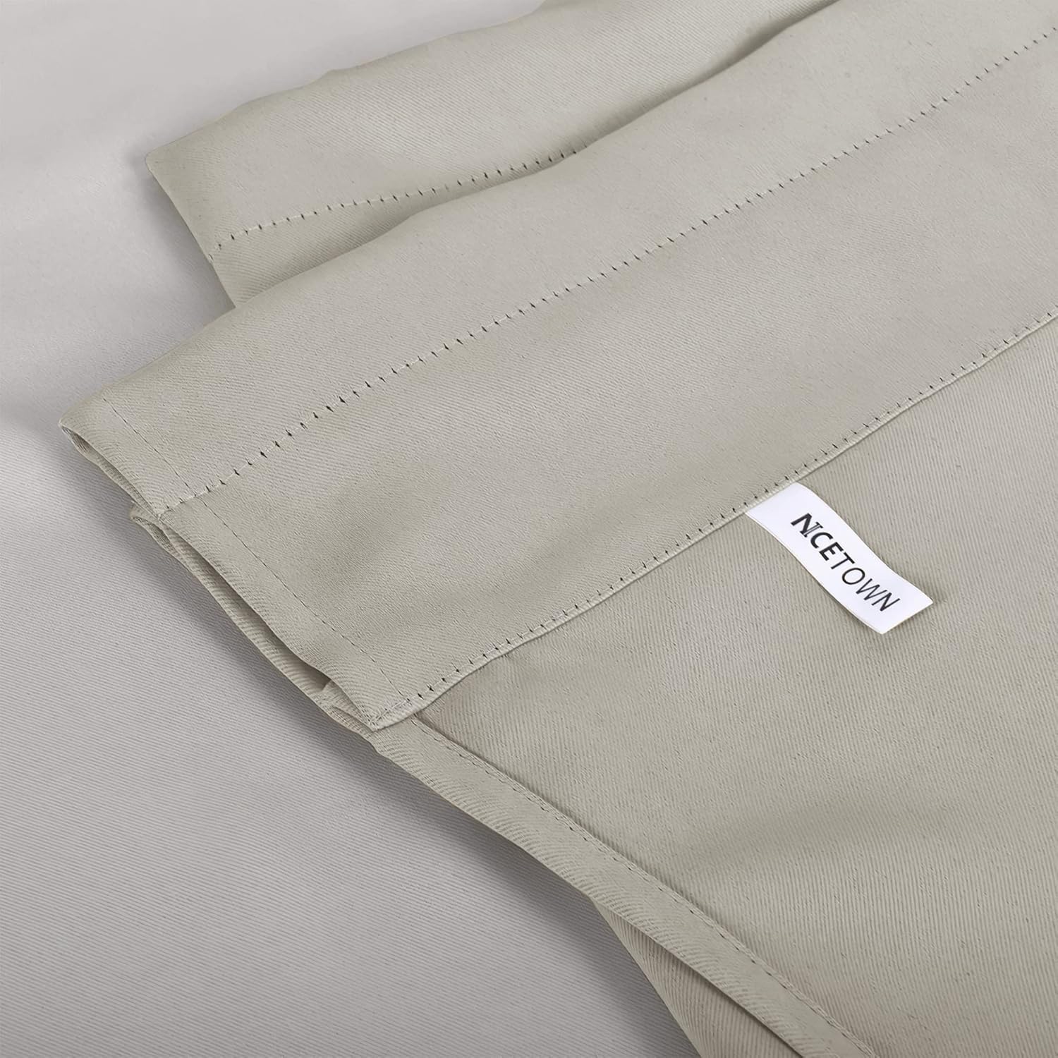 Folded light grey blackout curtain panel showing subtle twill fabric texture and a visible NCETOWN brand tag.