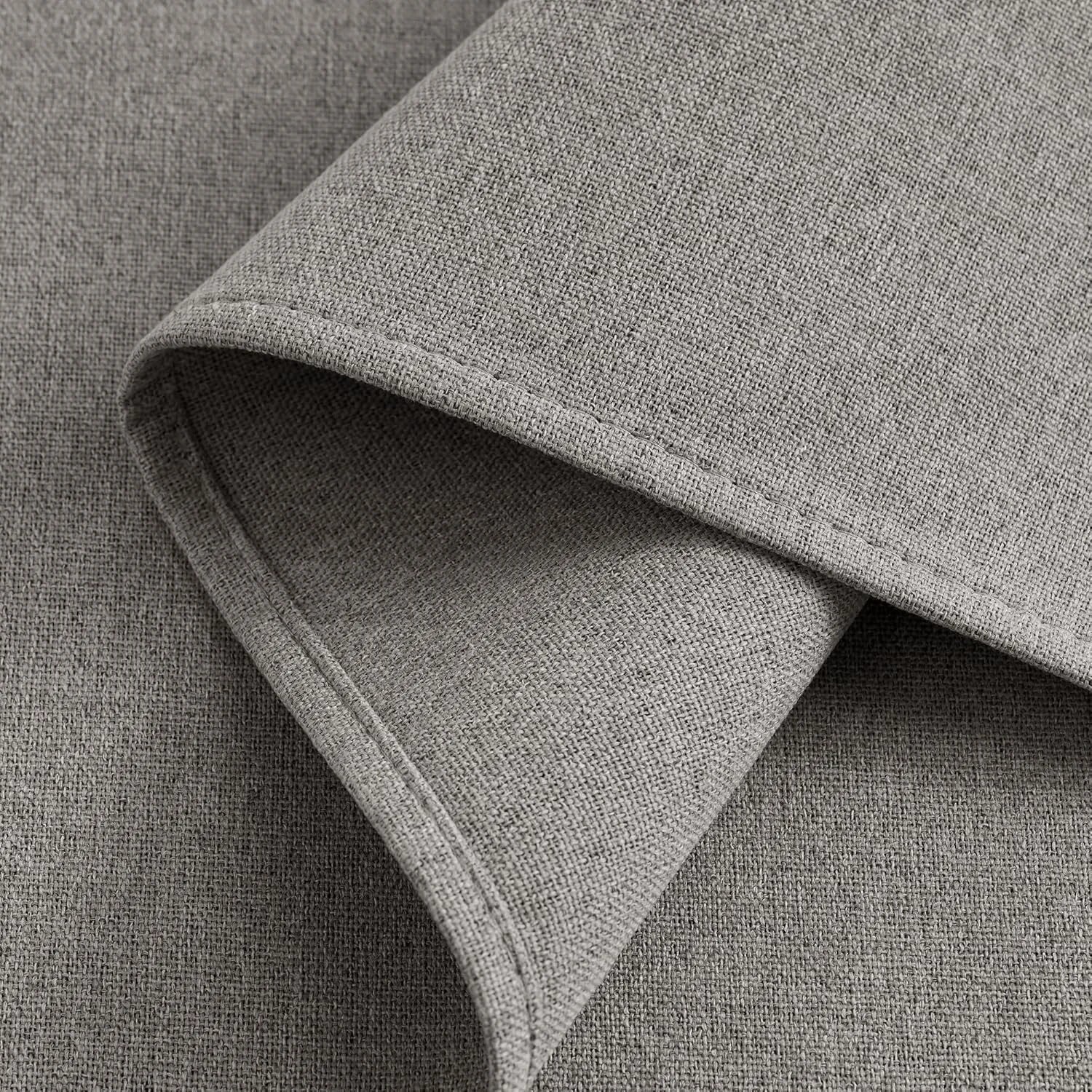 Close-up of light grey woven fabric, folded to reveal its detailed texture and subtle stitching.