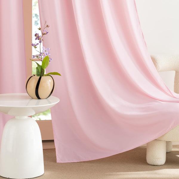 Light pink flowing window curtains draped elegantly, next to a modern white side table.